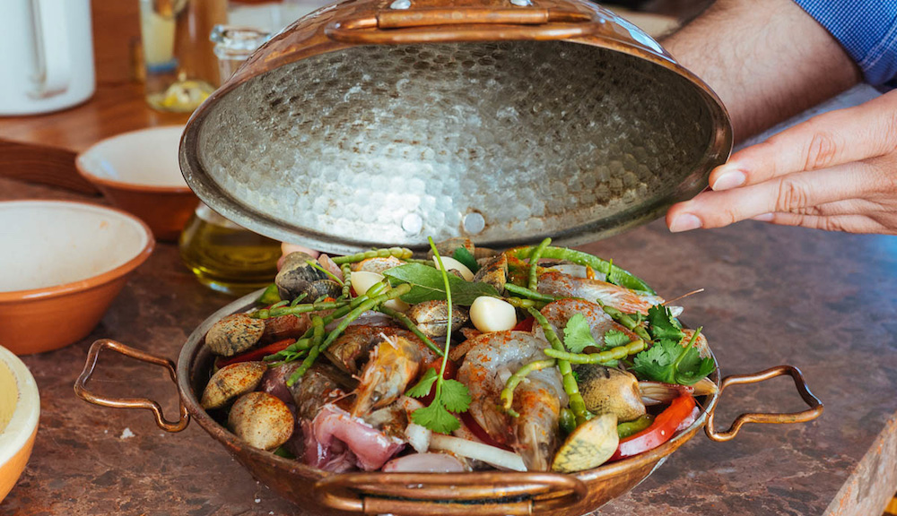 a person holding a plate of food on a table