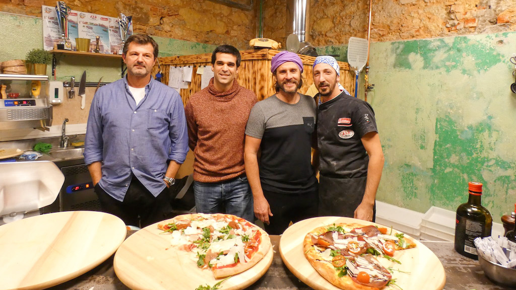 a group of people sitting at a table with a plate of pizza