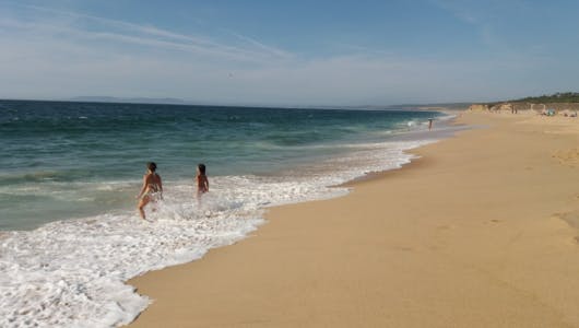 a person walking down a sandy beach next to the ocean