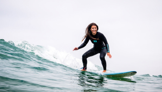 a man wearing a wet suit riding a surfboard on a wave