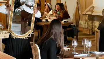 a person sitting at a table with wine glasses