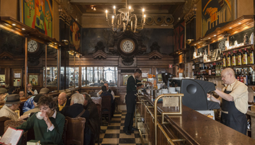 a group of people seated while drinking their coffee inside A Brasileira