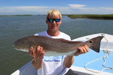 Man holding up large redfish on his boat