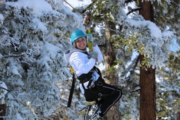 Woman on zip-line in front of snowy trees
