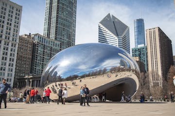 a group of people walking in front of a large city with Millennium Park in the background