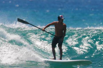 man stand up paddleboarding on wave