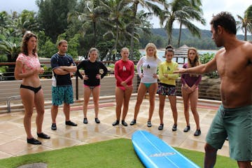 group learning how to surf on land with instructor