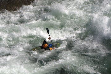 whitewater kayaker fighting through large rapids