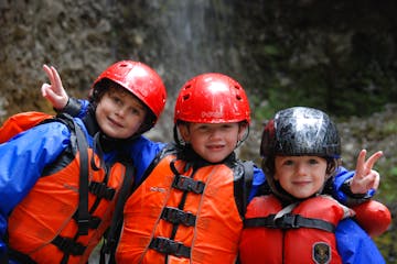 Three children in helmets and life jackets