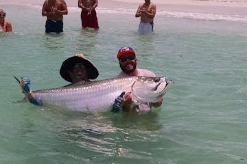 two men holding a tarpon out of the water in tampa