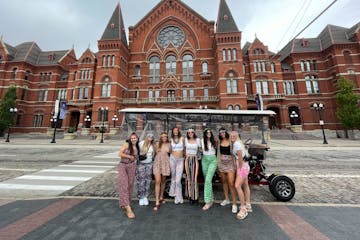 a group of people walking in front of Cincinnati Music Hall
