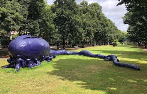 A blue sculpture of a sea animal with people around his head