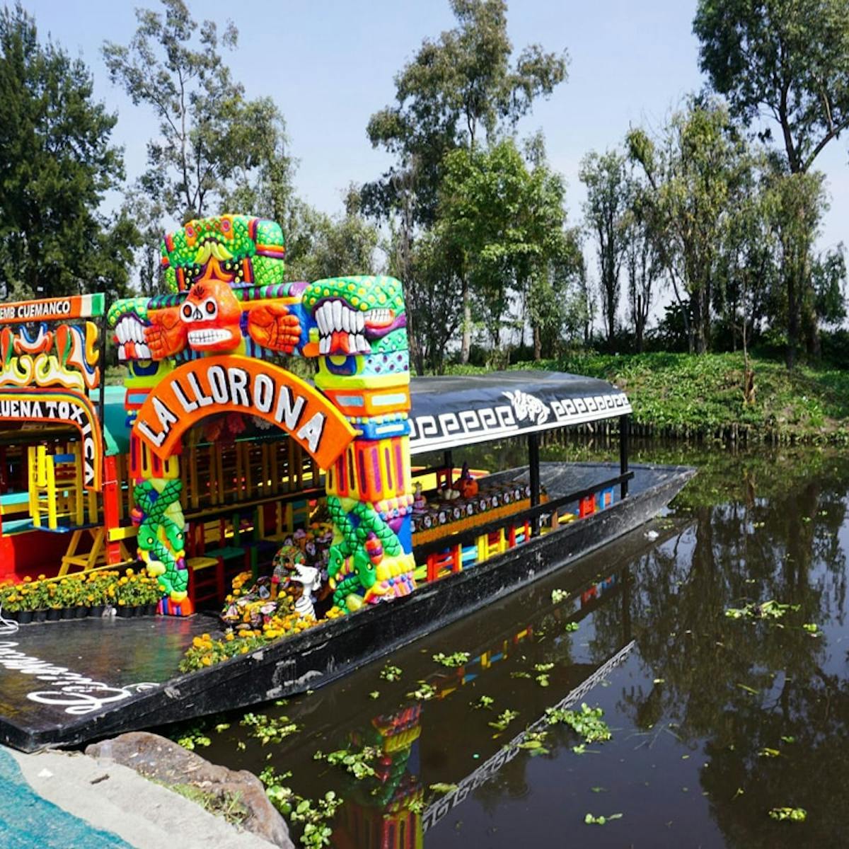 a colorful bus is parked on the side of a river