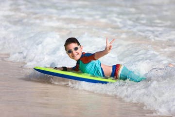 a young boy riding a wave on a surfboard in the water