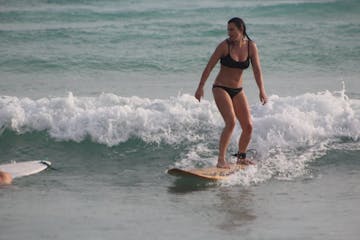 a young girl riding a wave on a surfboard in the water
