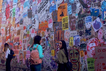 a group of people standing in front of a graffiti covered wall