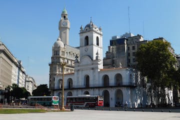 a group of people walking in front of a church with Buenos Aires Cabildo in the background