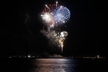 fireworks exploding at night over the water