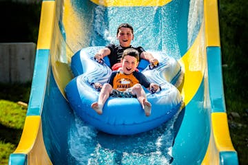 Two boys riding on a blowup donut on a waterslide