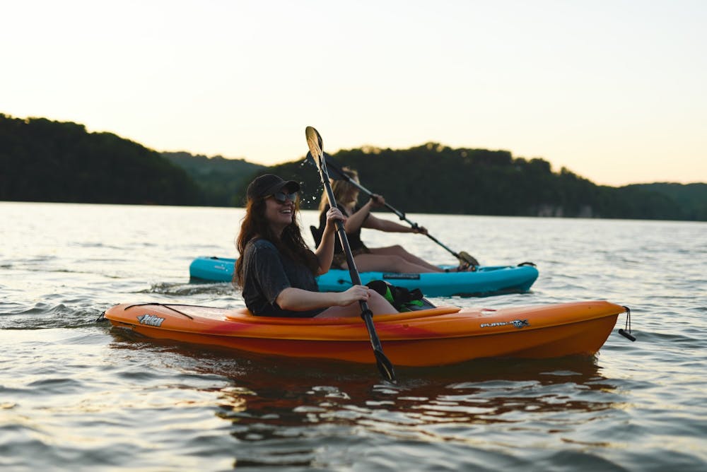 two girls kayaking as the sun sets