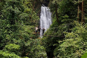 a waterfall in a forest at El Tigre Waterfalls also known as Cataratas El Tigre Monteverde