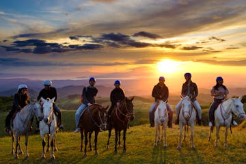 a group of people on horsebacks watching the sunset at Equus Monteverde Farm