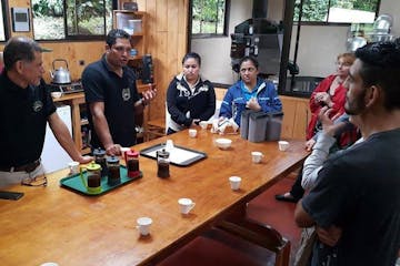a group of people sitting at a table learning about coffee at Monteverde Coffee Tour