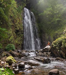 A tourist standing next to a Monteverde Waterfall.