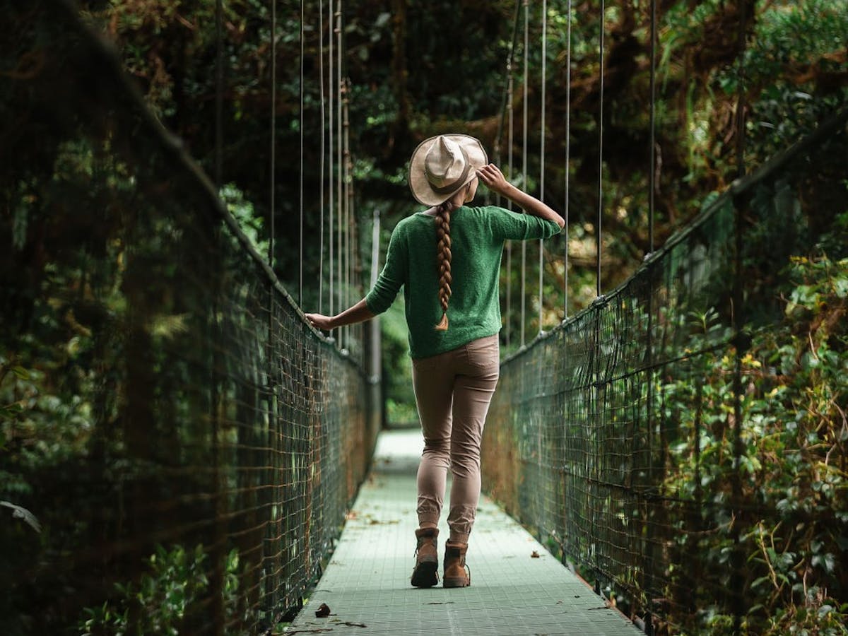 A person walking across a bridge on the Monteverde Hanging Bridges at Monteverde Tours