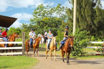 group of people on horses leaving a ranch