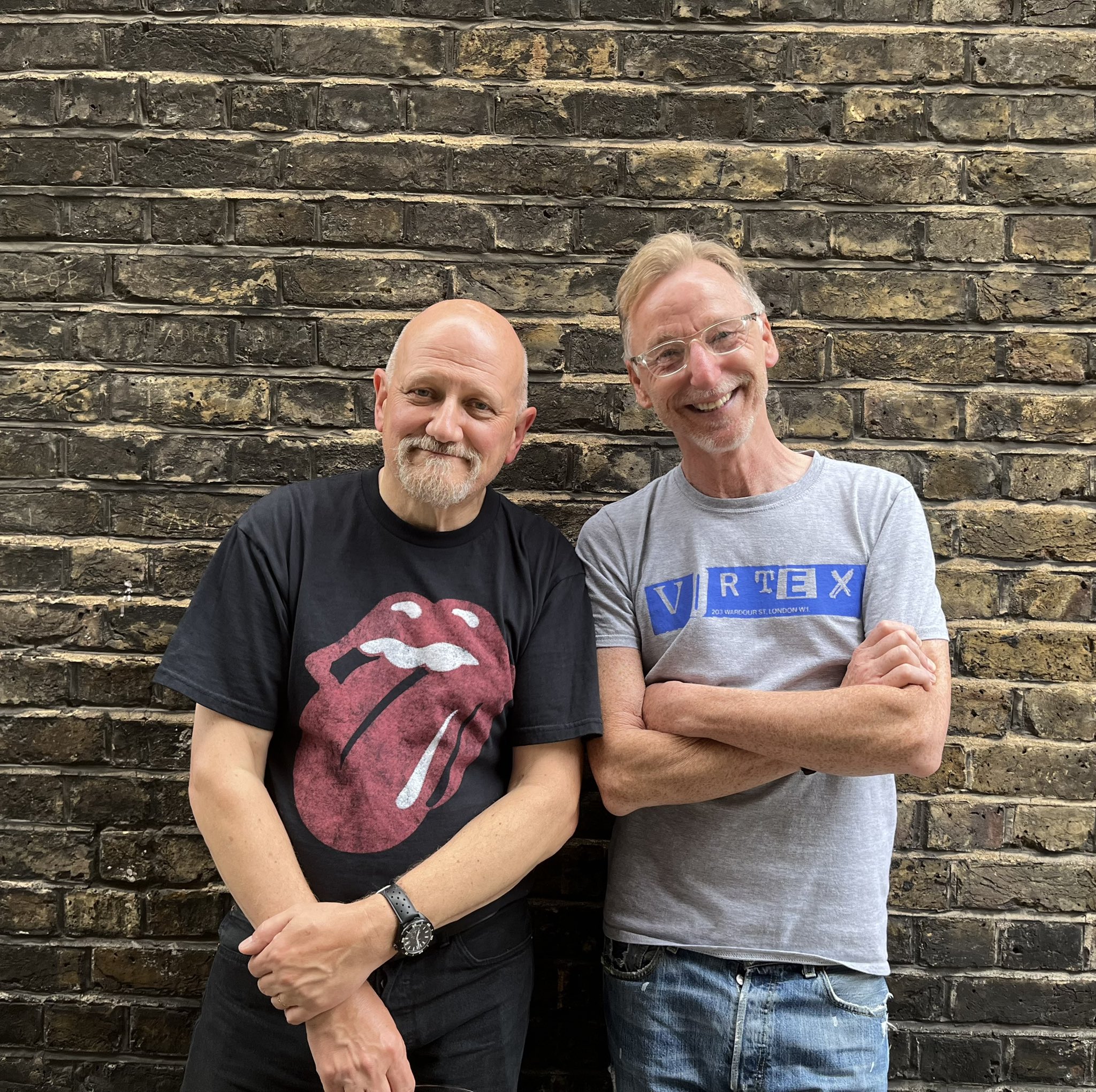 a man and a woman standing in front of a brick wall