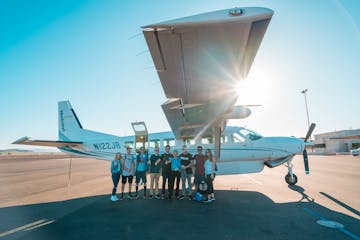 group of people standing in front of tour plane