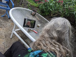 A cannasseur looking at an image of himself on a video screen on a table with a pipe and weed