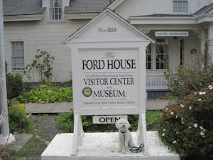 a dog sitting under the Ford House Museum sign