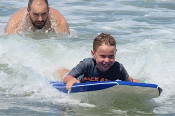 a young boy riding a wave on a surfboard in the water