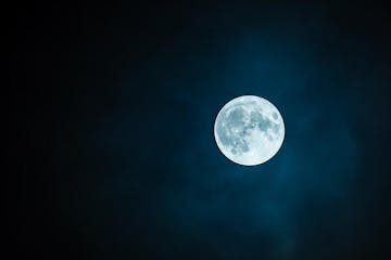 dark photo of the full moon in the night sky