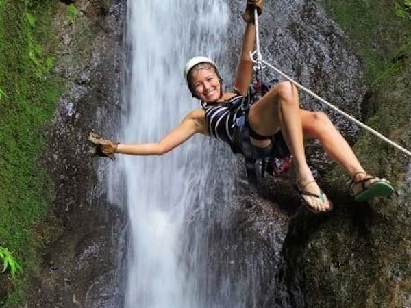 woman ziplining before a waterfall