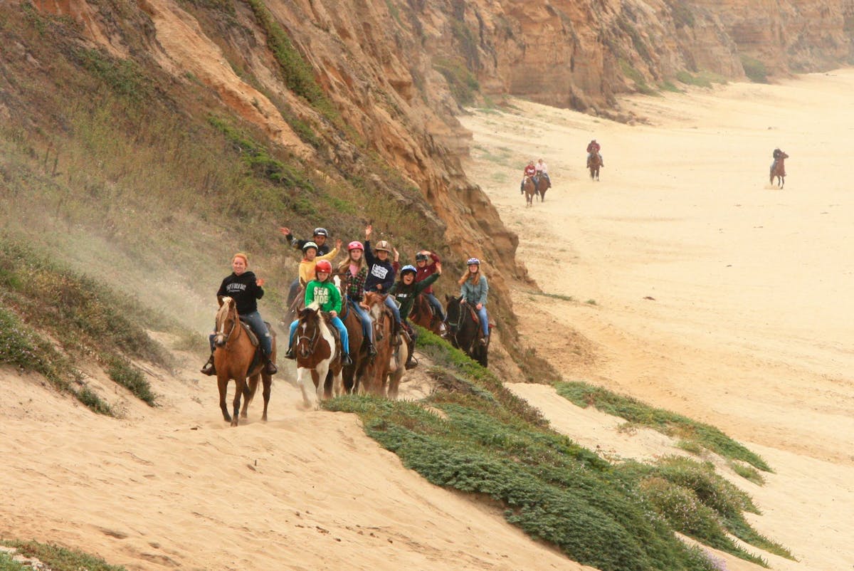 Riders waiving at the camera on a Horse back ride