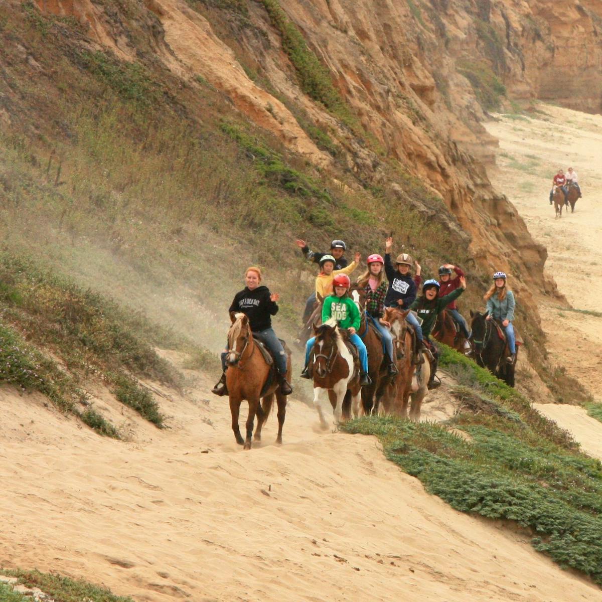 Riders waiving at the camera on a Horse back ride