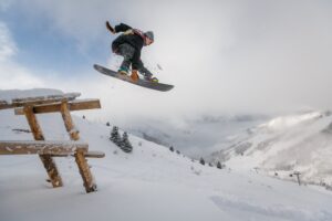 a man jumping in the air doing a trick on a snow board