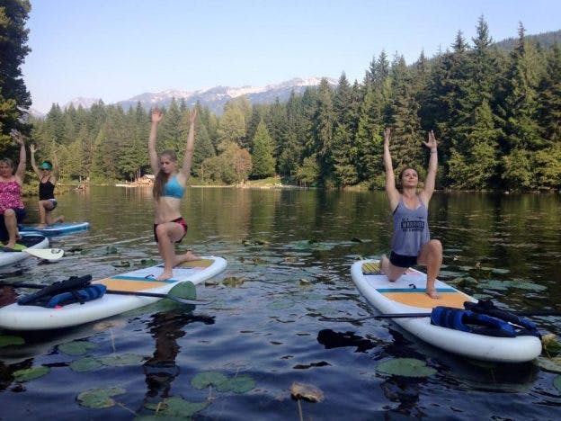 A group of women on a lake in Whistler standup paddleboard yoga.