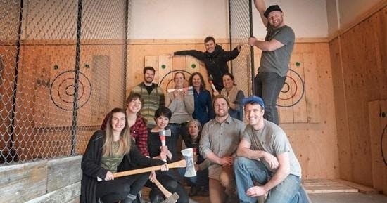 A group of friends posing in front a axe throwing targets