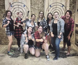 A group of women posing in plaid in front of axe targets
