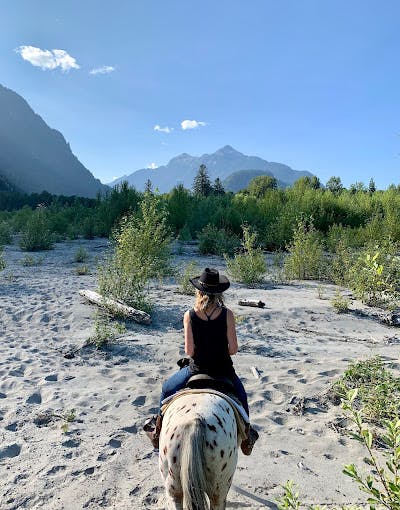 A person on a horse , mountain and river background