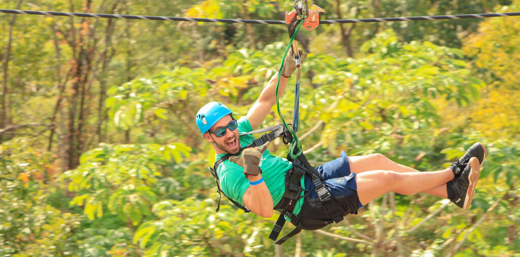 a guy ziplining over a forest