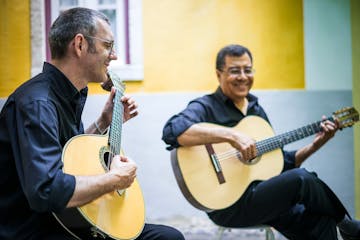 Two men holding guitars playing fado in Lisbon