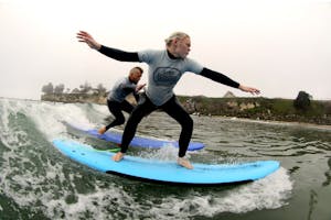 A surfing instructor teaching someone how to surf in Santa Cruz, CA