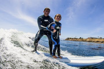 Bud Freitas instructing a young child how to surf in Santa Cruz, CA