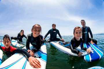 A group of young children posing on their surf boards during a surf lesson in Santa Cruz, CA