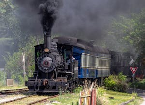 a steam engine on a train track with smoke coming out of it
